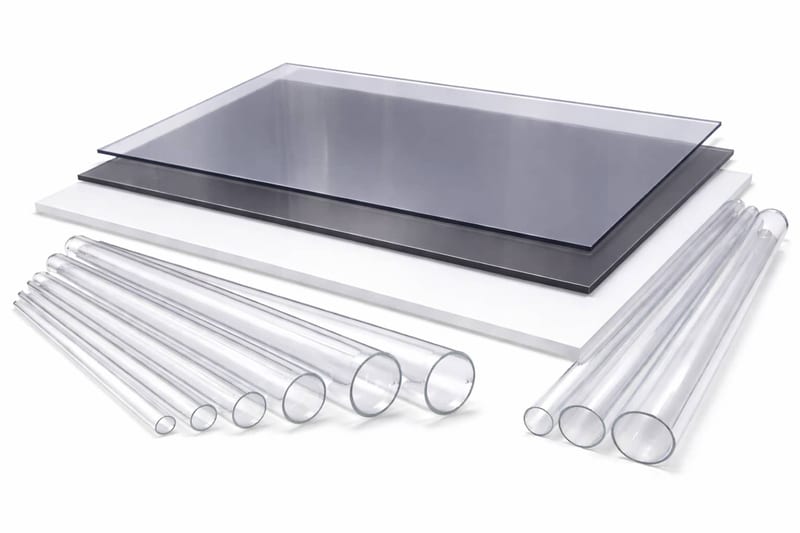 Polycarbonate sheets in clear, grey tint and opal, stacked beside clear polycarbonate tubes in a range of diameters